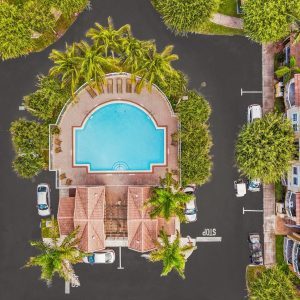 Aerial View Of Pool Area With Sun Chairs, And Palm Trees