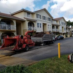Red Machine Picking Up Soil In Front Of Apartments